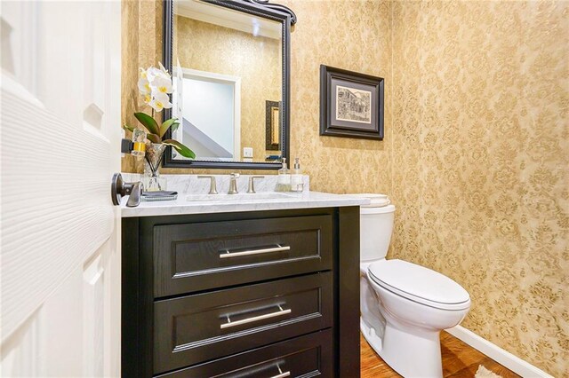 1605 Ridge Rd, Leavenworth, KS 66048 - bathroom with wallpapered walls, toilet, vanity, baseboards, and wood finished floors