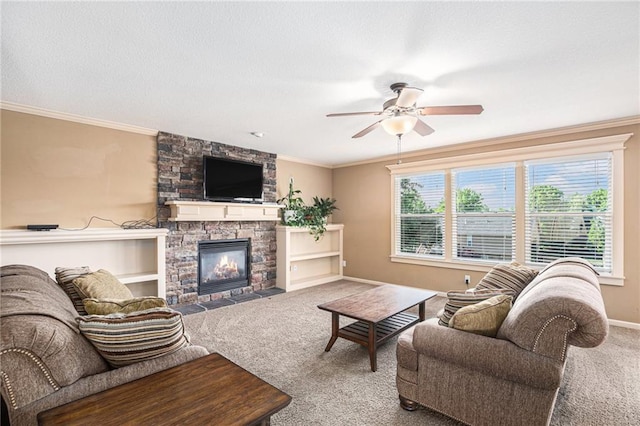 carpeted living area featuring ceiling fan, ornamental molding, baseboards, a stone fireplace, and a textured ceiling