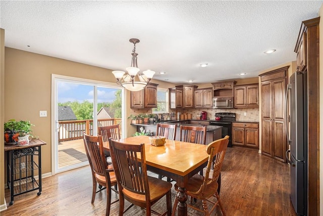 dining space featuring wood finished floors, a chandelier, a textured ceiling, baseboards, and recessed lighting