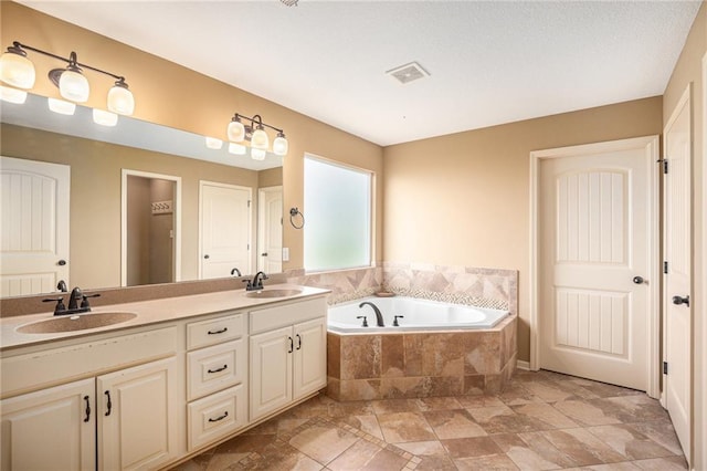 full bath featuring a bath, double vanity, and stone finish flooring