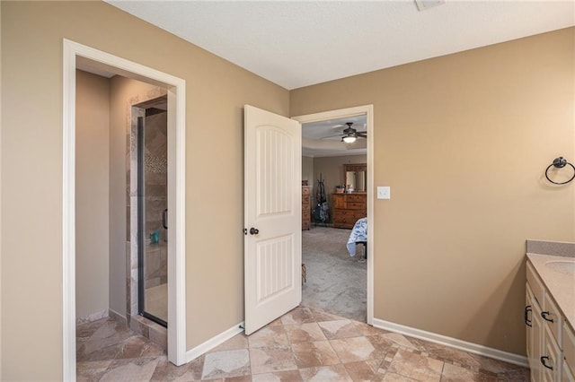 ensuite bathroom featuring vanity, a shower stall, baseboards, and a ceiling fan