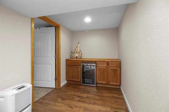 bar with wine cooler, dark wood-style floors, baseboards, and a textured wall