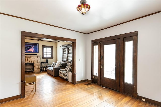 108 W 61st Ter, Kansas City, MO 64113 - foyer entrance with baseboards, a stone fireplace, light wood-style floors, and ornamental molding