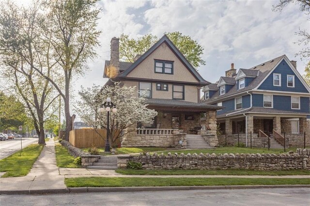 3744 Walnut St, Kansas City, MO 64111 - view of front of property with stone siding, covered porch, and fence