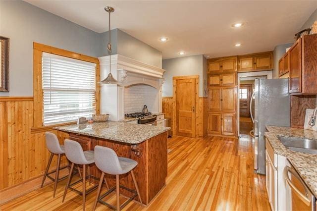 3744 Walnut St, Kansas City, MO 64111 - kitchen with appliances with stainless steel finishes, a wainscoted wall, healthy amount of natural light, light wood-type flooring, and a sink