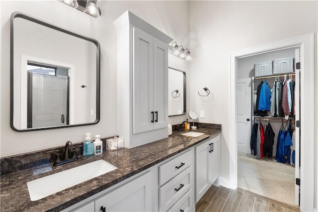 9424 N Belleview Ave, Kansas City, MO 64155 - bathroom featuring a stall shower, a walk in closet, double vanity, and wood finished floors
