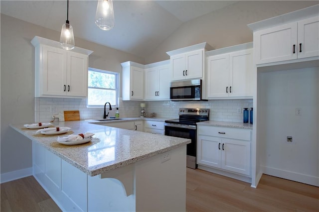 kitchen with appliances with stainless steel finishes, a peninsula, light wood-style floors, white cabinetry, and lofted ceiling