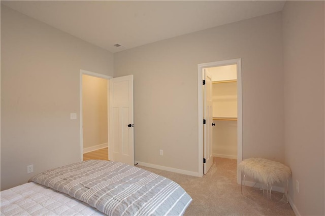 bedroom featuring carpet, a spacious closet, baseboards, and a closet