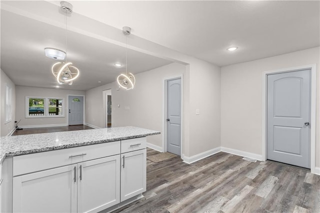 3107 N 34th St, Kansas City, KS 66104 - kitchen featuring white cabinets, wood finished floors, light stone countertops, baseboards, and hanging light fixtures