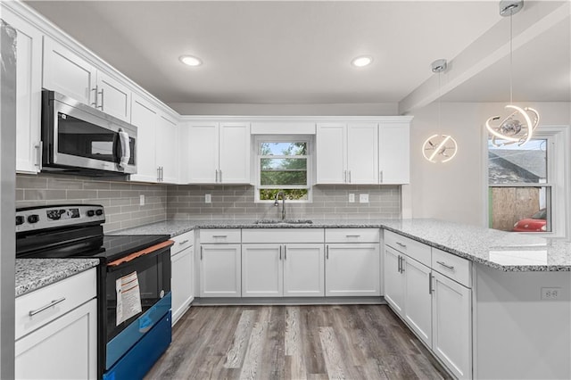 3107 N 34th St, Kansas City, KS 66104 - kitchen featuring electric range oven, stainless steel microwave, a sink, a peninsula, and white cabinetry