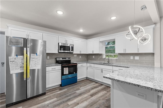 3107 N 34th St, Kansas City, KS 66104 - kitchen featuring appliances with stainless steel finishes, a sink, white cabinetry, light wood-type flooring, and light stone counters