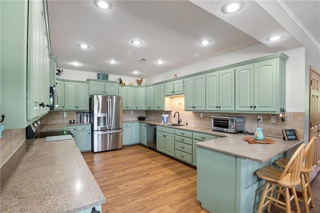 9 SW 500th Rd, Warrensburg, MO 64093 - kitchen featuring stainless steel appliances, a sink, a peninsula, green cabinets, and decorative backsplash