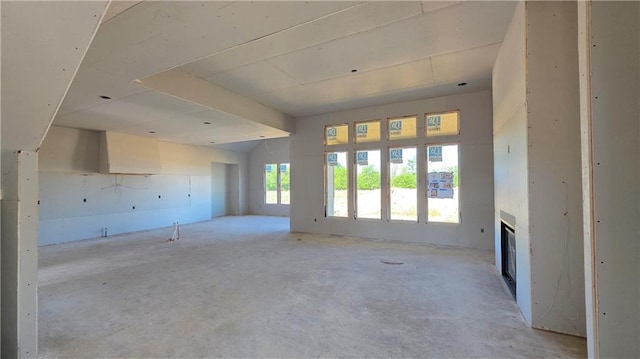 unfurnished living room featuring unfinished concrete flooring and a glass covered fireplace