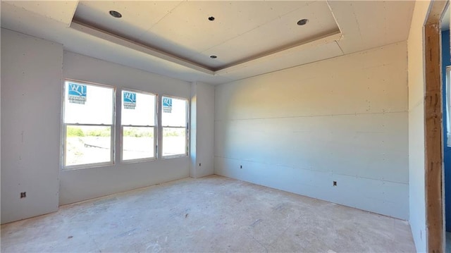 empty room featuring a raised ceiling and unfinished concrete flooring
