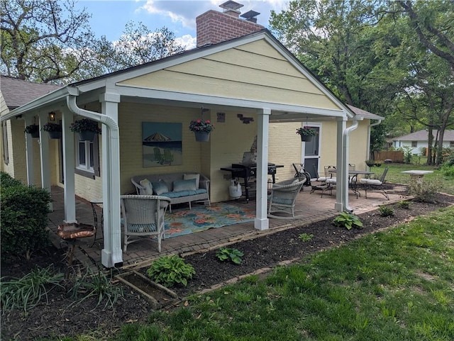back of property featuring a chimney, a patio area, an outdoor hangout area, and fence