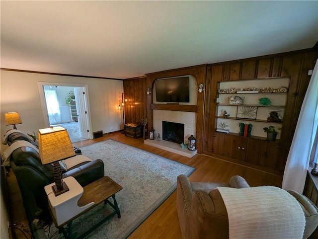 living area featuring a fireplace with raised hearth, wood finished floors, and baseboards