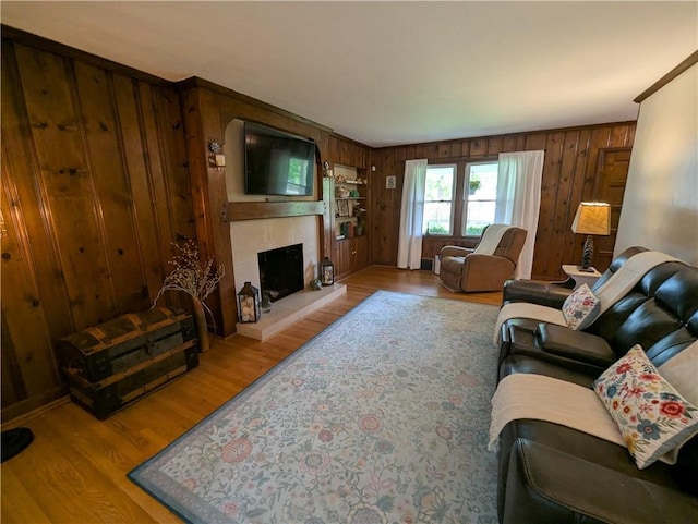 living area featuring a fireplace, wood walls, and wood finished floors