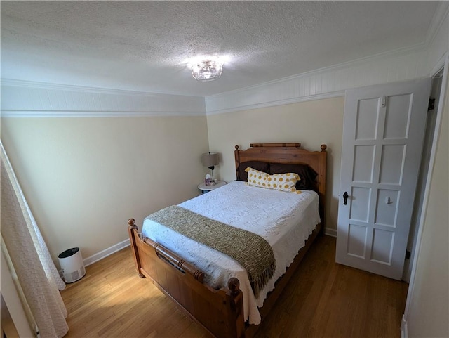 bedroom with ornamental molding, light wood finished floors, a textured ceiling, and baseboards