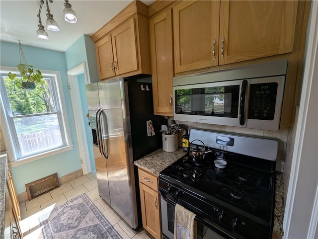 kitchen featuring stainless steel appliances, light tile patterned floors, light stone counters, and baseboards
