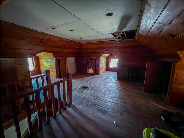 additional living space featuring wooden walls, wood-type flooring, and arched walkways