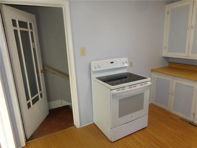2011 S Broadway St, Pittsburg, KS 66762 - kitchen with electric range, light wood-type flooring, and white cabinetry