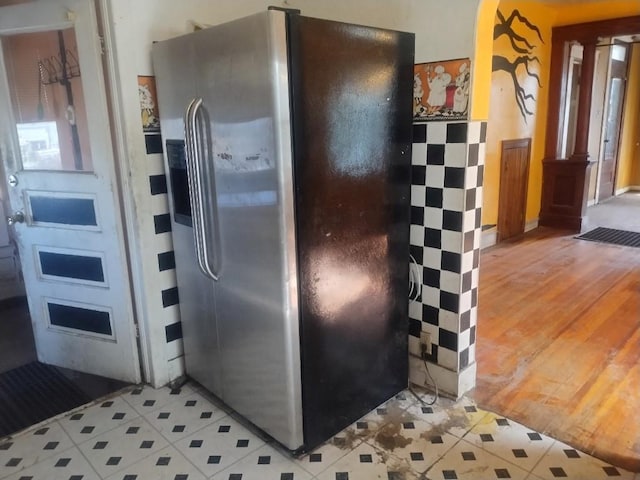 kitchen featuring stainless steel refrigerator with ice dispenser, light tile patterned floors, and arched walkways
