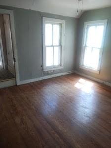 spare room featuring wood finished floors, healthy amount of natural light, and baseboards
