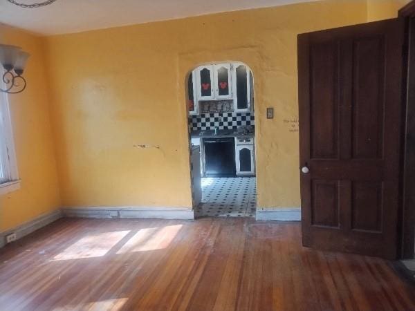 spare room with baseboards and wood finished floors