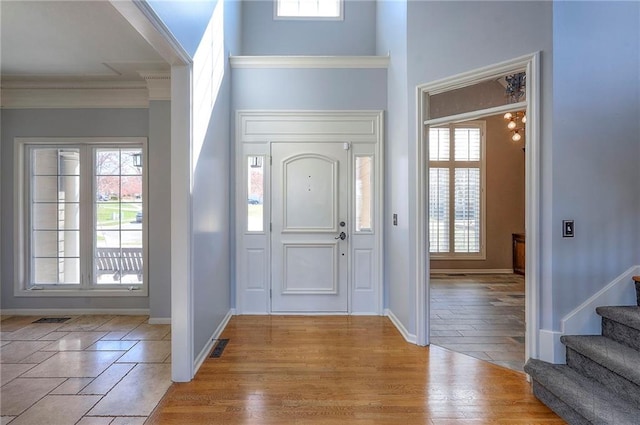 entrance foyer featuring crown molding, stairs, light wood-style floors, and baseboards
