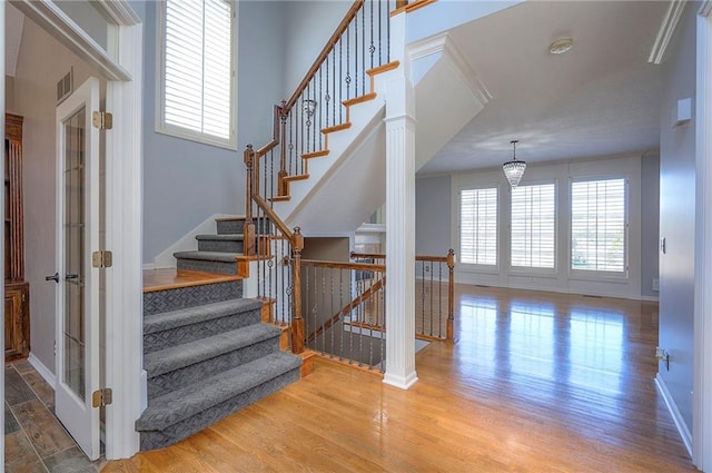 stairway featuring wood finished floors, healthy amount of natural light, and baseboards