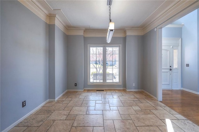 unfurnished dining area with crown molding, stone tile floors, and baseboards