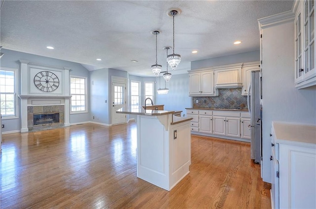 kitchen featuring custom exhaust hood, a kitchen bar, a textured ceiling, decorative backsplash, and black cooktop