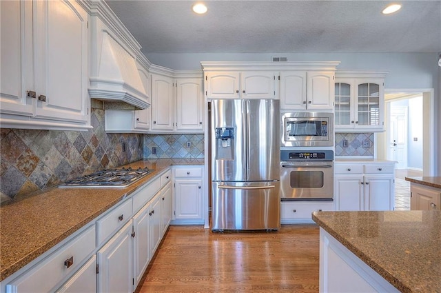 kitchen with stainless steel appliances, premium range hood, white cabinetry, recessed lighting, and decorative backsplash