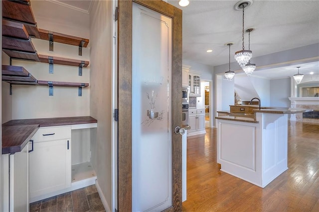 kitchen featuring dark countertops, dark wood-style floors, white cabinetry, appliances with stainless steel finishes, and decorative light fixtures