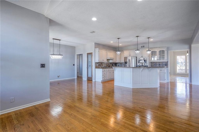 unfurnished living room featuring baseboards, a textured ceiling, light wood-style floors, and recessed lighting