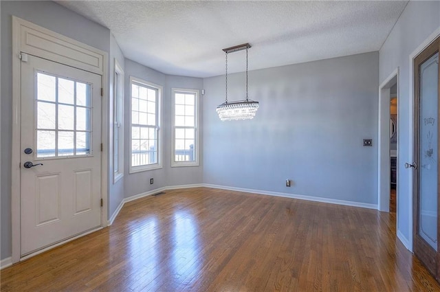 entryway with wood finished floors, a chandelier, baseboards, and a textured ceiling