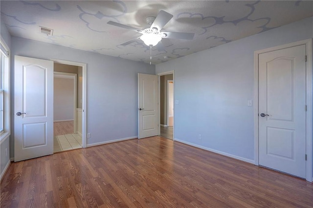 unfurnished bedroom featuring wood finished floors, baseboards, and ceiling fan
