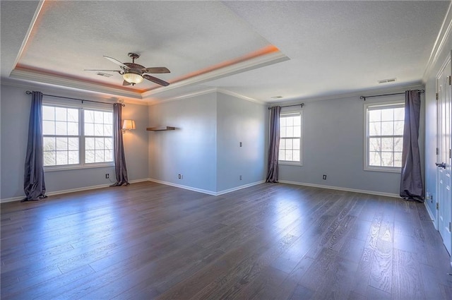 empty room with a raised ceiling, crown molding, a textured ceiling, ceiling fan, and dark wood-style flooring