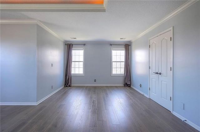 spare room featuring dark wood finished floors, baseboards, ornamental molding, and a textured ceiling