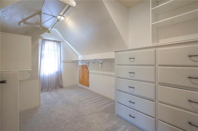 spacious closet with lofted ceiling and light colored carpet