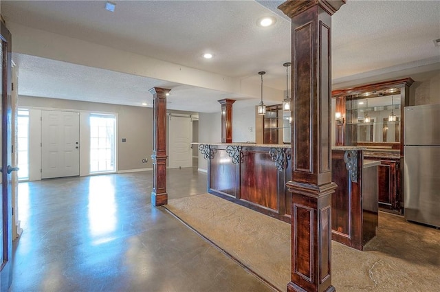 bar featuring ornate columns, freestanding refrigerator, a textured ceiling, finished concrete floors, and baseboards