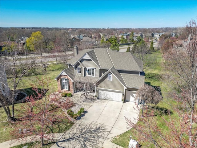 view of front facade featuring an attached garage, concrete driveway, a chimney, a shingled roof, and a residential view