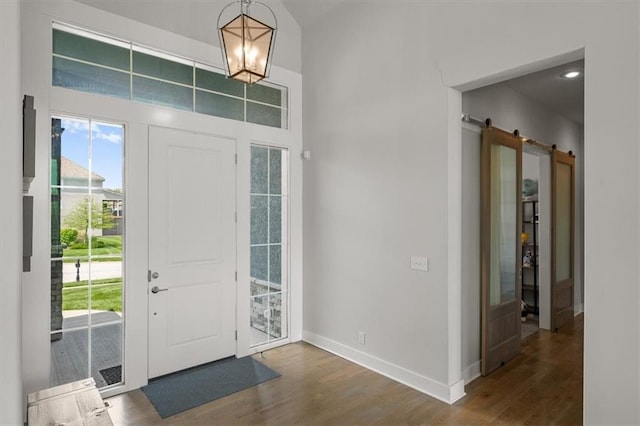 10523 N Dalton Ave, Kansas City, MO 64154 - foyer entrance with wood finished floors, a barn door, baseboards, and a chandelier
