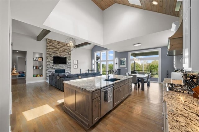 10523 N Dalton Ave, Kansas City, MO 64154 - kitchen with stainless steel appliances, a sink, wood finished floors, an island with sink, and light stone countertops