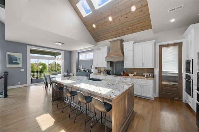 10523 N Dalton Ave, Kansas City, MO 64154 - kitchen with custom exhaust hood, stainless steel oven, a kitchen bar, a spacious island, and a skylight