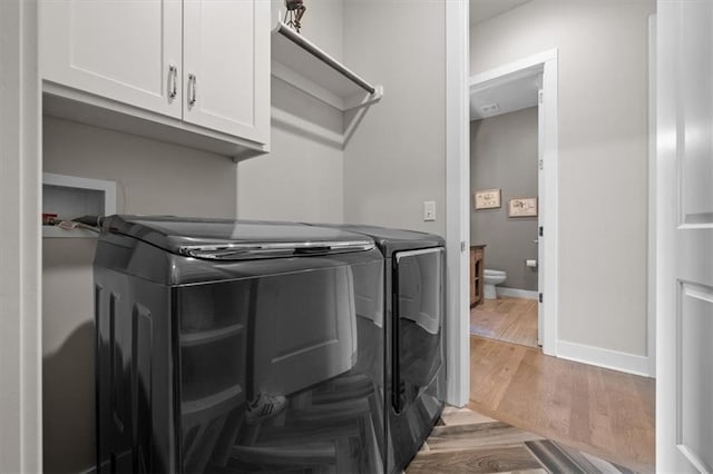 10523 N Dalton Ave, Kansas City, MO 64154 - clothes washing area featuring washer and dryer, cabinet space, light wood-style floors, and baseboards