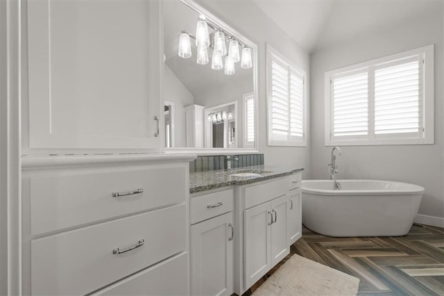 10523 N Dalton Ave, Kansas City, MO 64154 - full bathroom featuring vaulted ceiling, a freestanding tub, vanity, and baseboards