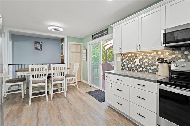 201 N Cleveland Ave, Belton, MO 64012 - kitchen featuring stainless steel appliances, light wood-style flooring, backsplash, and white cabinets