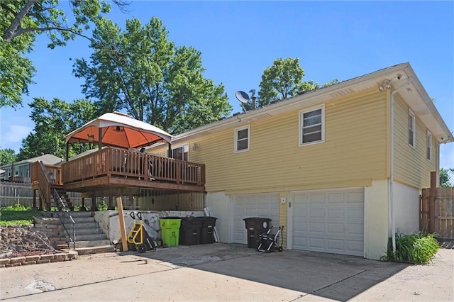 201 N Cleveland Ave, Belton, MO 64012 - rear view of house featuring an attached garage, stairs, concrete driveway, and a wooden deck