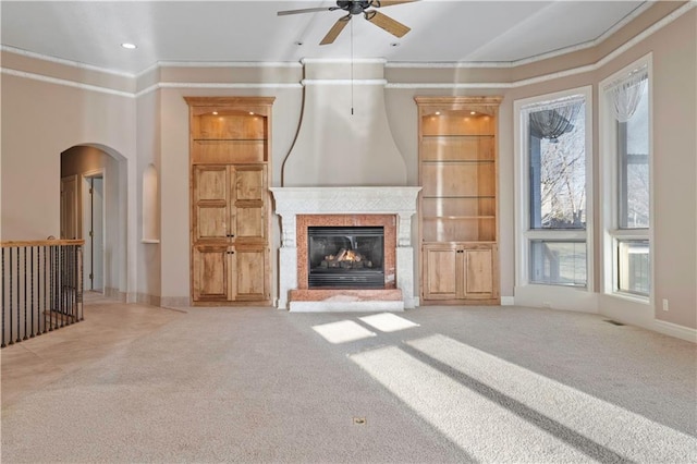 4704 W 152nd St, Leawood, KS 66224 - unfurnished living room featuring arched walkways, crown molding, a ceiling fan, carpet, and a glass covered fireplace